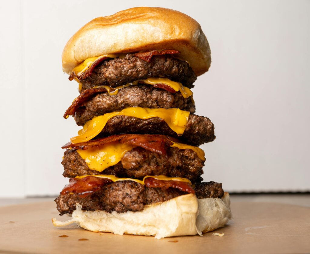 Delicious triple-stacked bacon cheeseburger with melted cheese, perfect for food lovers.